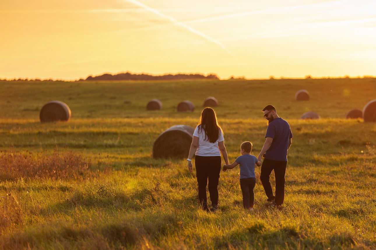 farm family walks across field of round bales